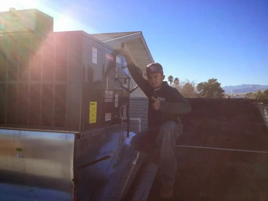 HVAC technician performing Air Duct Repair on a rooftop unit in Gouverneur